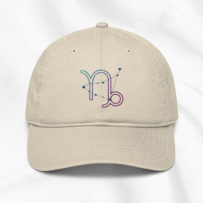 Beige organic cotton baseball cap with embroidered capricorn graphic on white background