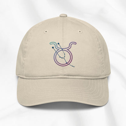 Beige cap with a colorful embroidered Taurus zodiac symbol on a white background