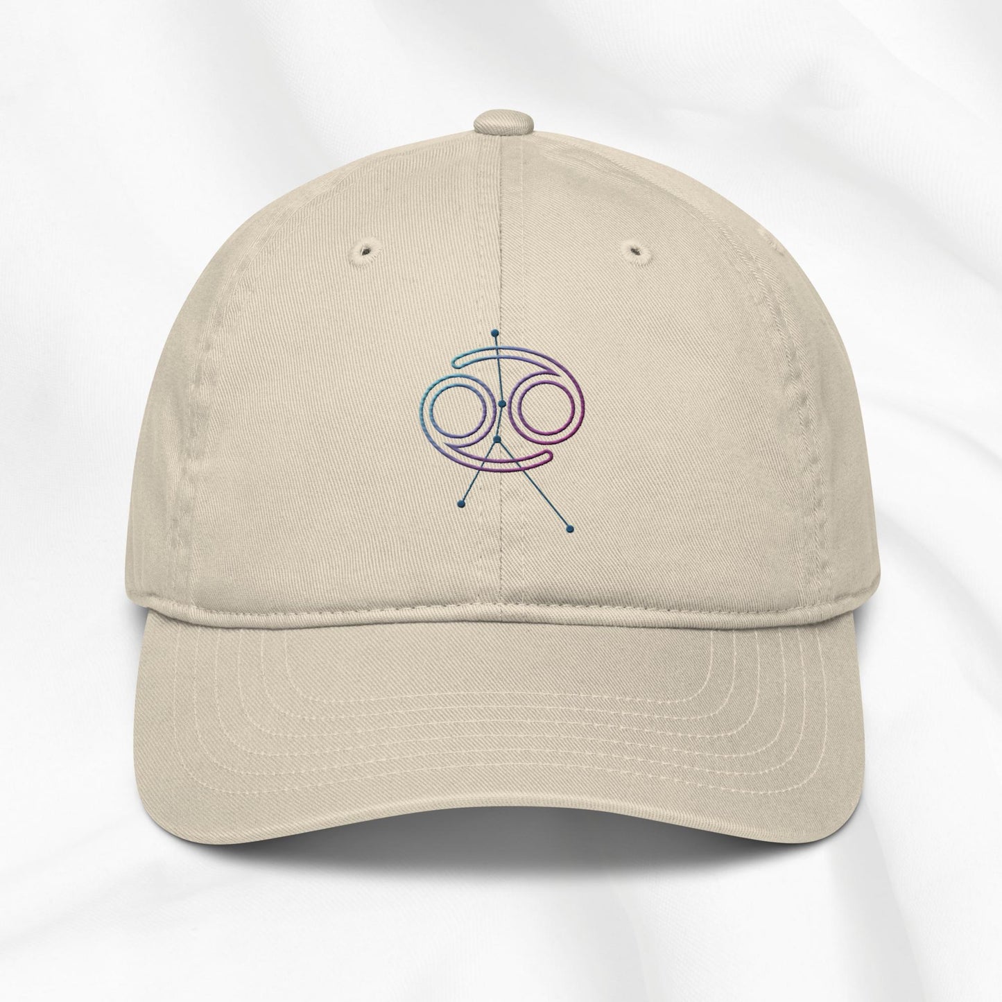 Beige organic cotton baseball cap with embroidered Cancer zodiac graphic on a white background