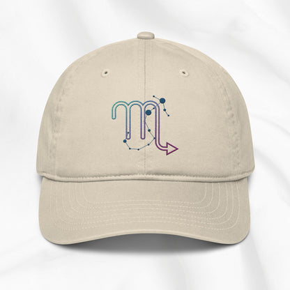 Beige organic cotton baseball cap with an embroidered scorpio zodiac graphic on a white background. 
