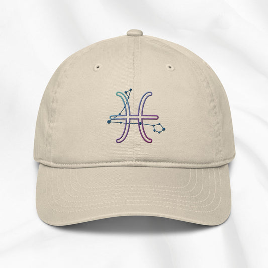 Beige organic cotton baseball cap with an embroidered pisces zodiac design on a white background